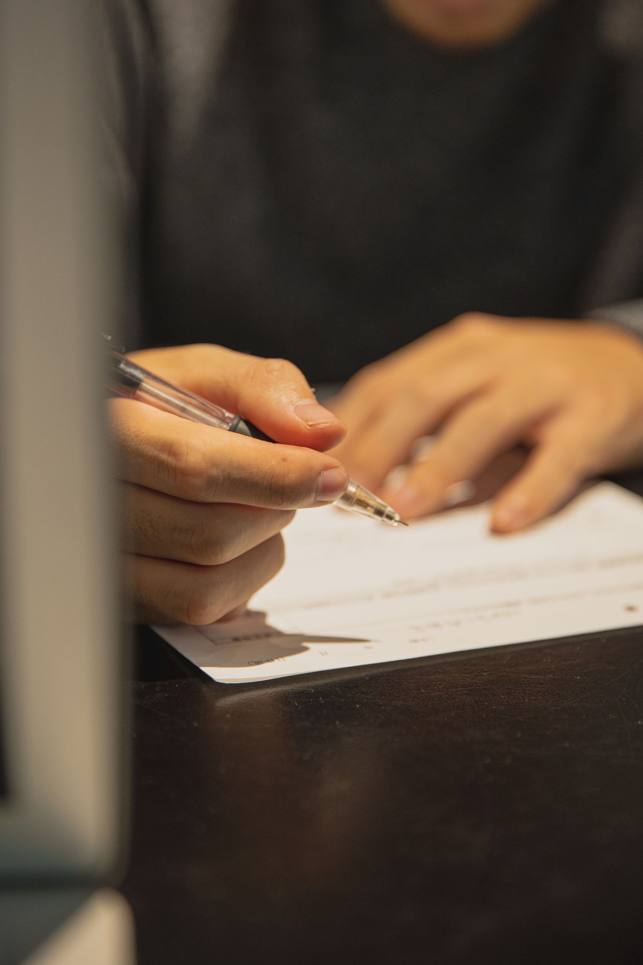 Mão escrevendo com caneta sobre papel, representando a elaboração da carta de apresentação
