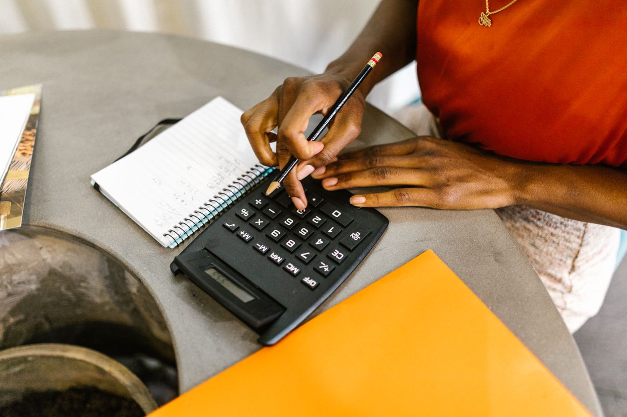 Mulher usando calculadora para conferir os gastos do mês